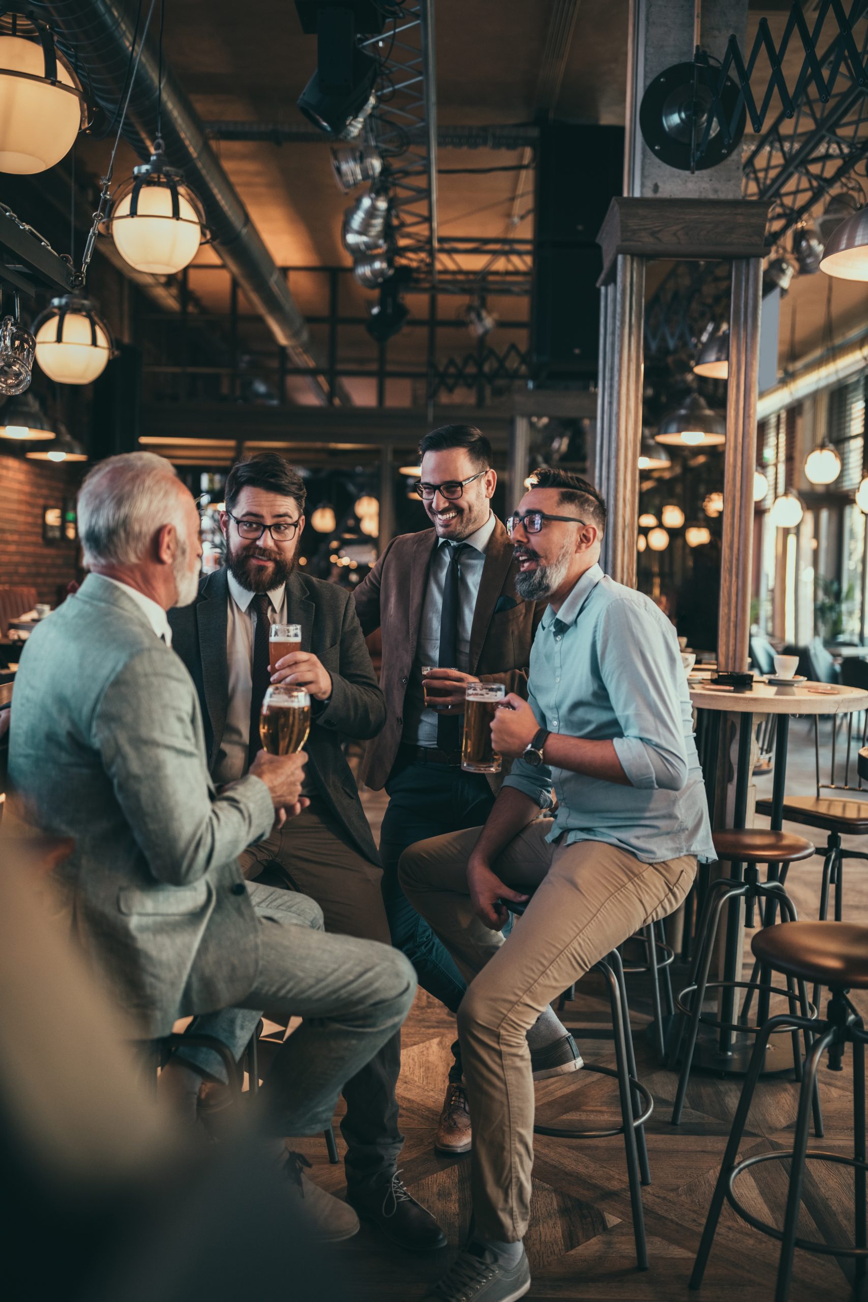 Team of colleagues socializing at the bar and drinking beers